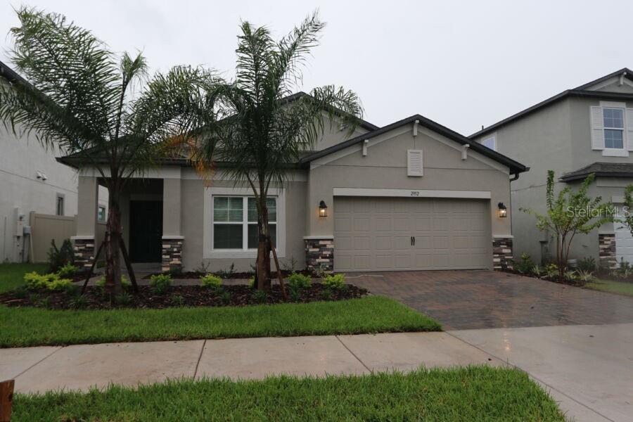 A covered front porch features a dark blue door, a table with two chairs, and decor — 2952 MARINE GRASS DRIVE, WIMAUMA, FL