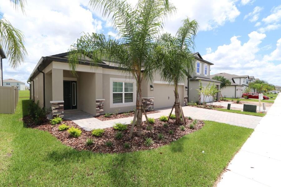 A single-story house exterior features a paved driveway, a two-car garage, and a palm tree — 2952 MARINE GRASS DRIVE, WIMAUMA, FL