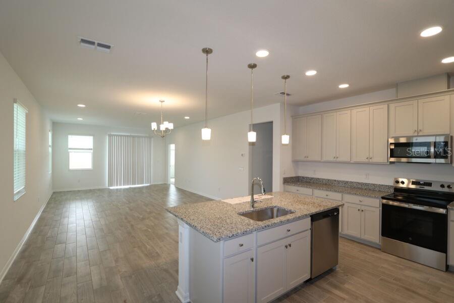 A kitchen with light-colored cabinets, granite countertops, a central island, and coastal-themed decor — 2952 MARINE GRASS DRIVE, WIMAUMA, FL