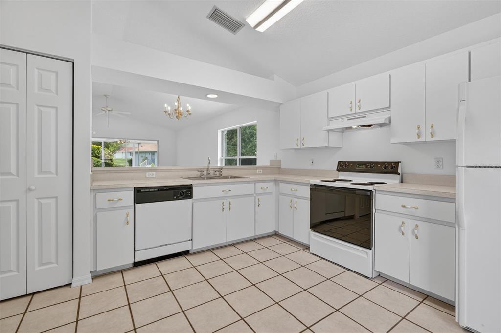 A kitchen with white cabinets, white appliances, and light-colored tile flooring — 660 W SUNSET STRIP DRIVE, BEVERLY HILLS, FL