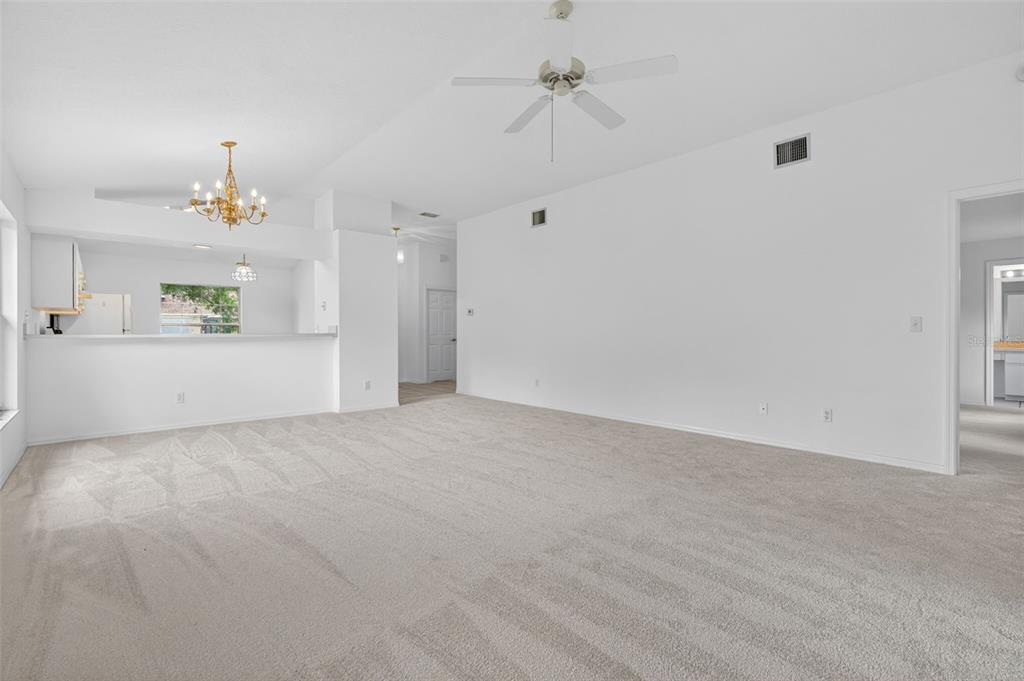 A spacious living room with beige carpeting, white walls, a ceiling fan, and a breakfast bar — 660 W SUNSET STRIP DRIVE, BEVERLY HILLS, FL
