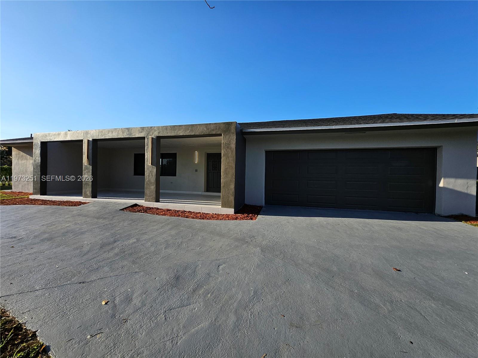 A single-story house features a dark gray garage, a covered porch, and a concrete driveway — 11761 NW 27th Ct, Plantation FL 33323, PLANTATION, FL