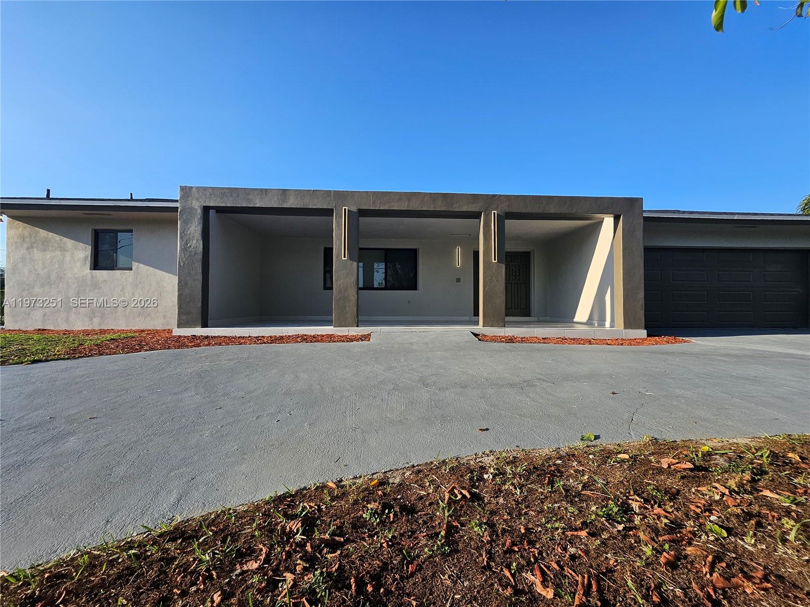 The exterior of a single-story house features a large covered entryway and a concrete driveway — 11761 NW 27th Ct, Plantation FL 33323, PLANTATION, FL