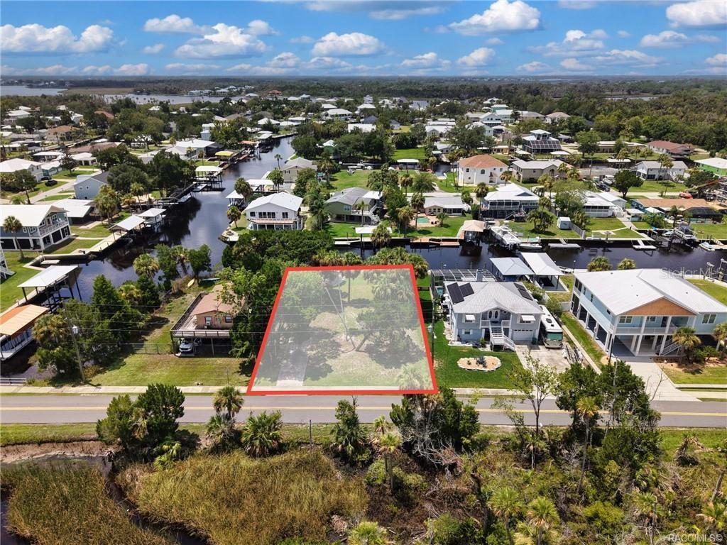 An aerial view shows a vacant, tree-covered waterfront lot outlined in red along a road — 2020 NW 19TH STREET, CRYSTAL RIVER, FL