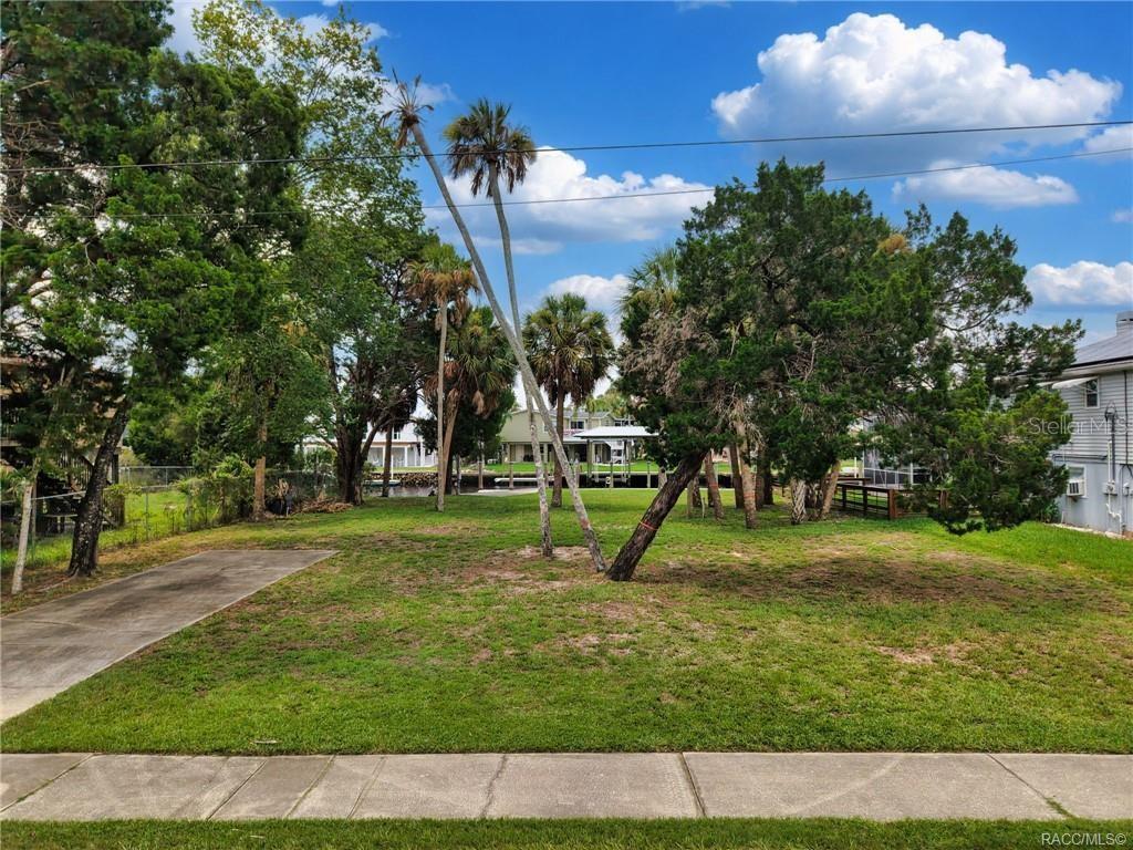A grassy vacant lot with several trees and a concrete driveway leads toward a canal — 2020 NW 19TH STREET, CRYSTAL RIVER, FL