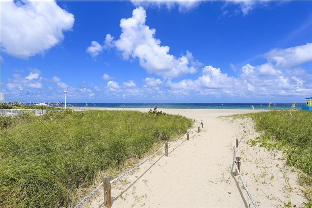 A sandy path leads through beach grass toward the ocean under a blue sky — 405 N Ocean Boulevard # 507, Pompano Beach FL 33062, POMPANO BEACH, FL