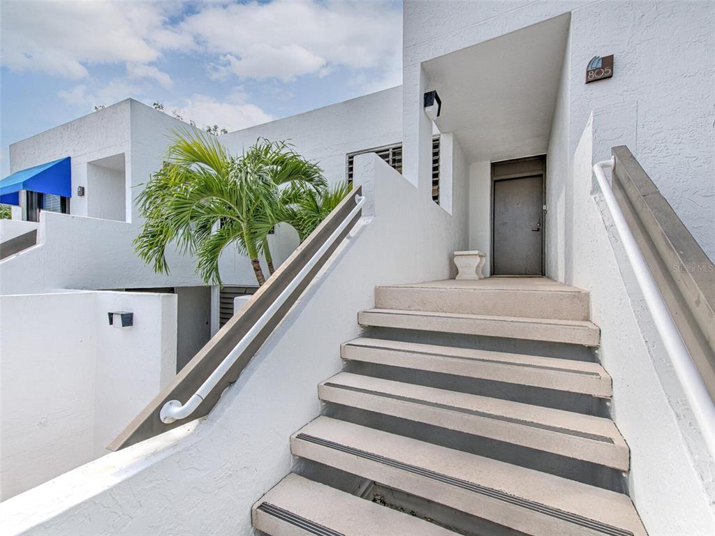 Concrete stairs with metal railings lead up to the entrance of a white building — 805 BAYPORT WAY UNIT 805, LONGBOAT KEY, FL