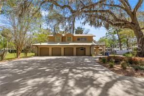 A three-car garage sits beneath the second story of a house shaded by large trees — 4817 RIVERSIDE DRIVE, YANKEETOWN, FL