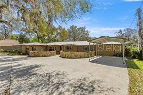 A single-story house with a stone-walled front patio and a metal carport on a driveway — 4817 RIVERSIDE DRIVE, YANKEETOWN, FL