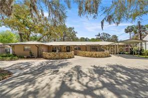 A single-story house with a stone retaining wall and a carport under large oak trees — 4817 RIVERSIDE DRIVE, YANKEETOWN, FL