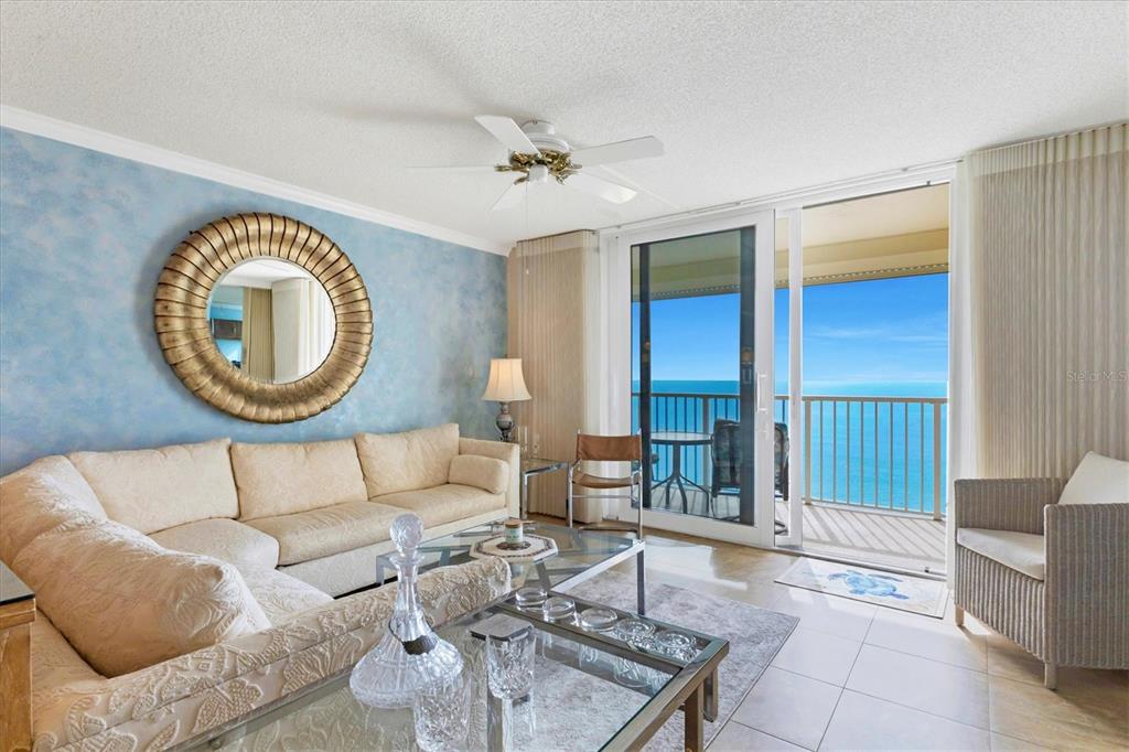 A living room with a blue accent wall, a large mirror, and a balcony overlooking water — 4485 GULF OF MEXICO DRIVE UNIT PH2, LONGBOAT KEY, FL