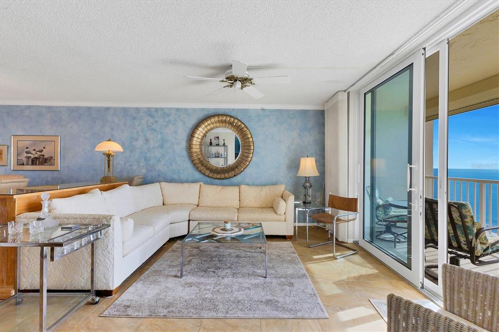 A living room features a white sectional sofa, a glass coffee table, and a blue wall — 4485 GULF OF MEXICO DRIVE UNIT PH2, LONGBOAT KEY, FL