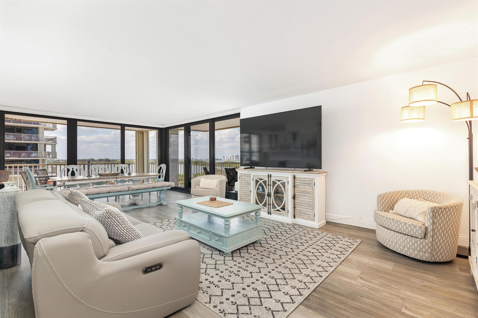 A living room features a light-colored sofa, a coffee table, and a large wall-mounted television — 5480 N Ocean Drive, Riviera Beach FL 33404, RIVIERA BEACH, FL