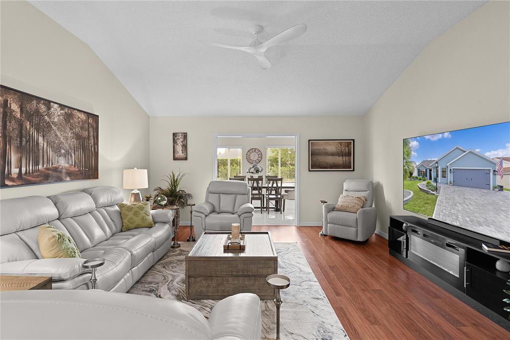 A living room with light gray leather furniture, a wood coffee table, and wood flooring — 1795 HAGOOD LOOP, THE VILLAGES, FL