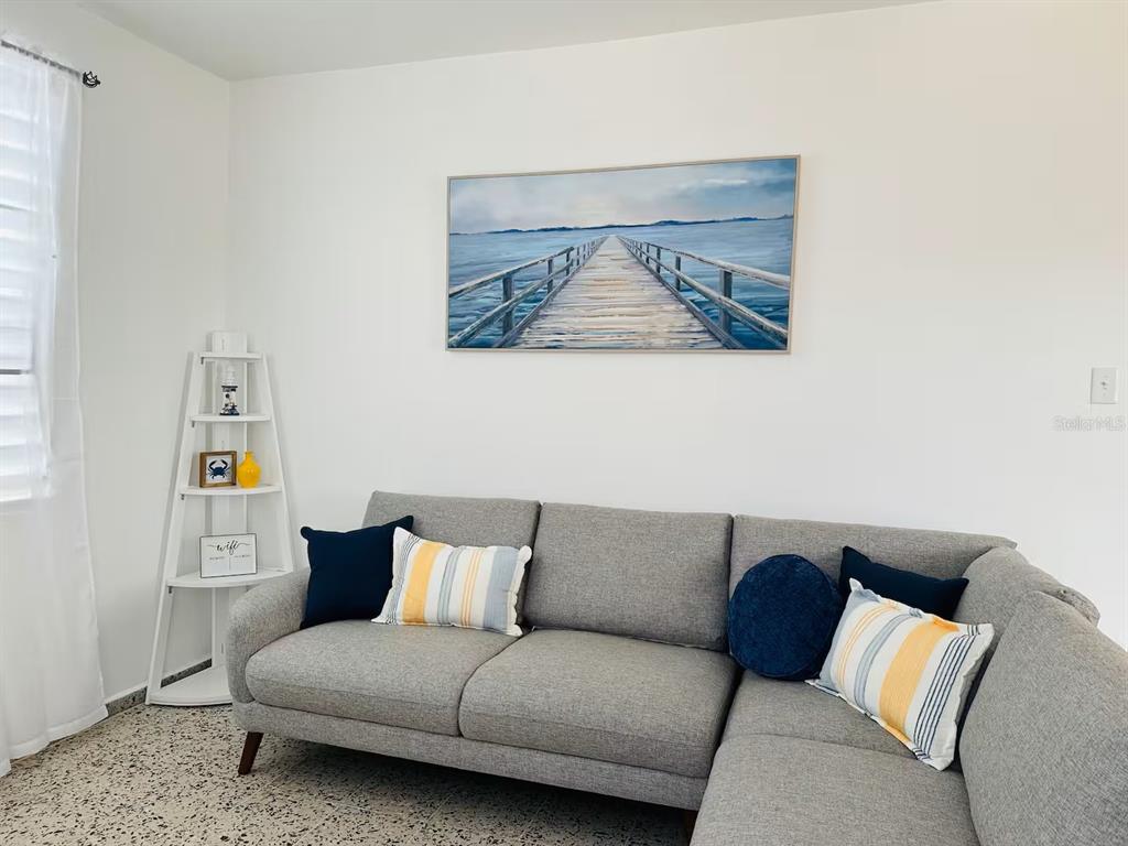 A living room features a gray sectional sofa, a corner shelf, and a pier wall art — Calle II 2 3301 COMBATE, BOQUERON, PR