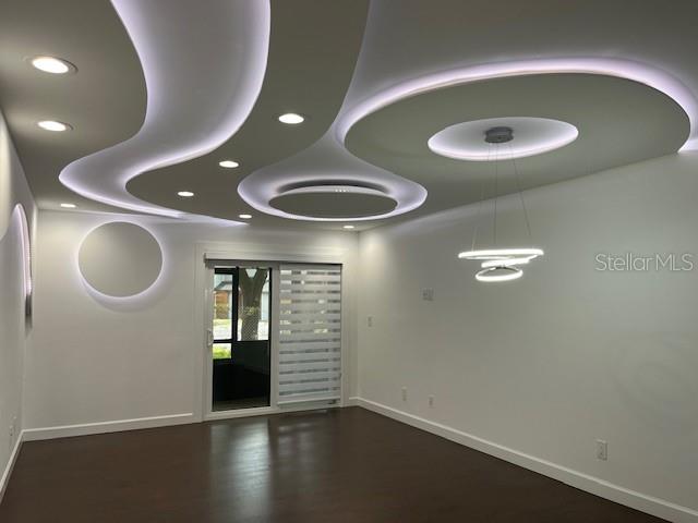 A room with dark wood flooring and a modern, curved, illuminated drop ceiling design — 1734 FOXHALL CIRCLE UNIT -, KISSIMMEE, FL