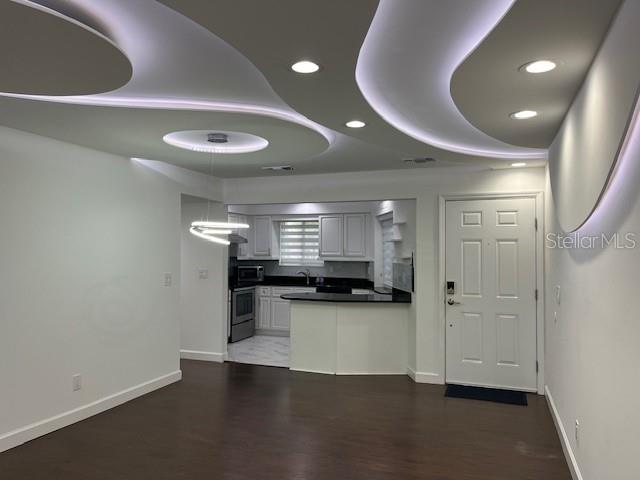 An open-concept living area features a modern curved ceiling design with recessed lighting and a kitchen — 1734 FOXHALL CIRCLE UNIT -, KISSIMMEE, FL