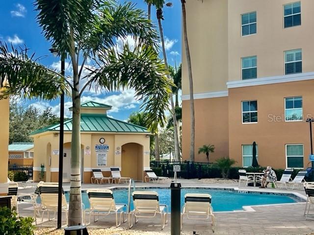 A swimming pool sits in front of a multi-story building with palm trees nearby — 2060 MATECUMBE KEY ROAD UNIT 2102, PUNTA GORDA, FL