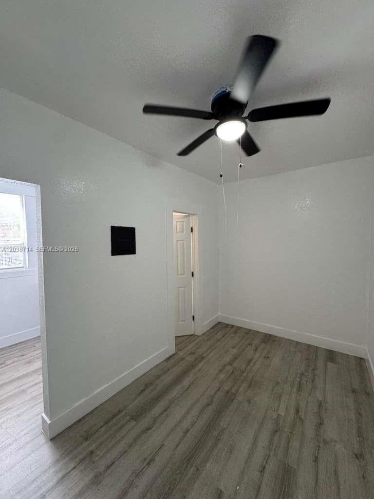 A room with white walls, a ceiling fan, and light-colored wood-look flooring — MIAMI, FL