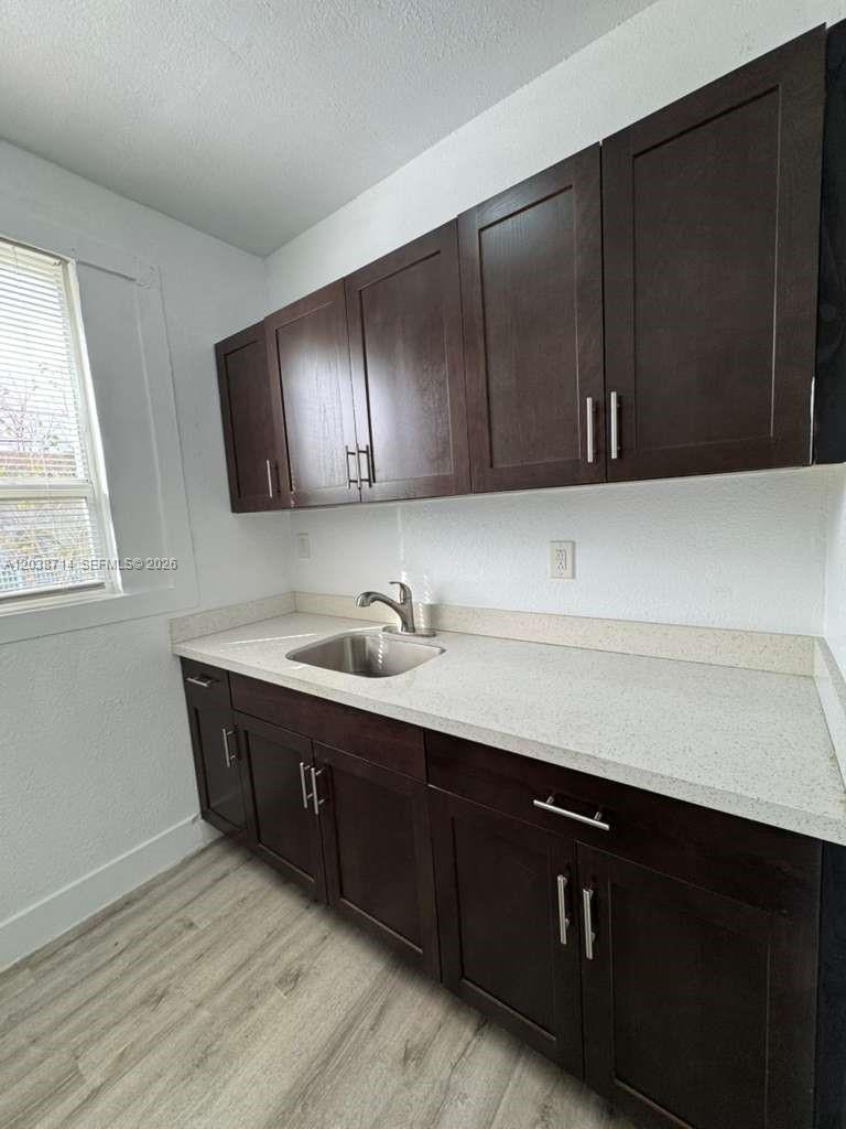 A kitchen features dark wood cabinets, a light-colored countertop, and a stainless steel sink — MIAMI, FL
