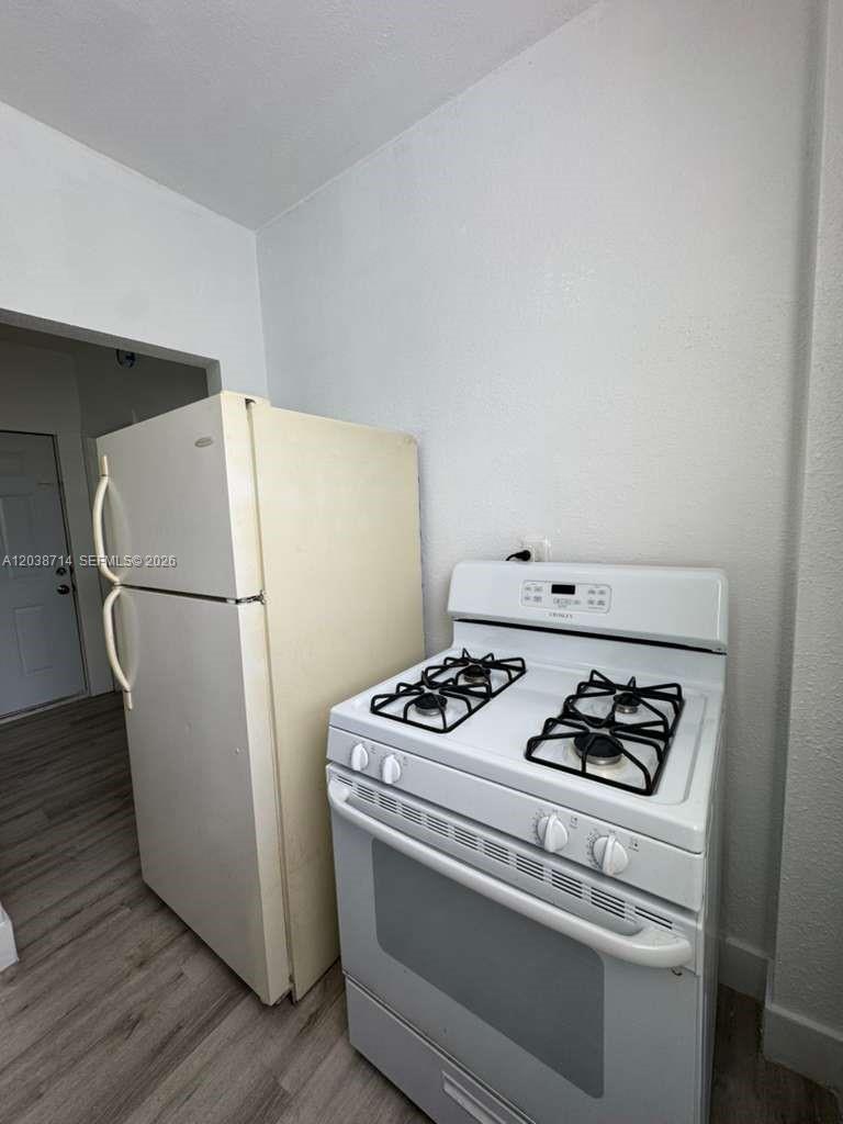 A kitchen features a white gas stove next to a cream-colored refrigerator — MIAMI, FL