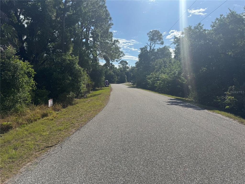 A paved road winds through a wooded area with a small sign on the left — Lot 8 SAN SALVADOR ROAD, NORTH PORT, FL