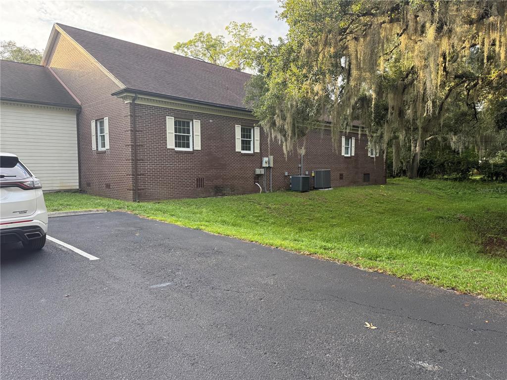 A side view of a brick building with white shutters and a paved parking area — 500 NE 8TH AVENUE, OCALA, FL