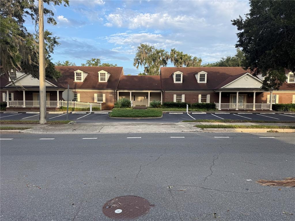 A low-rise brick office building with dormer windows and a covered front entrance faces a parking lot — 500 NE 8TH AVENUE, OCALA, FL