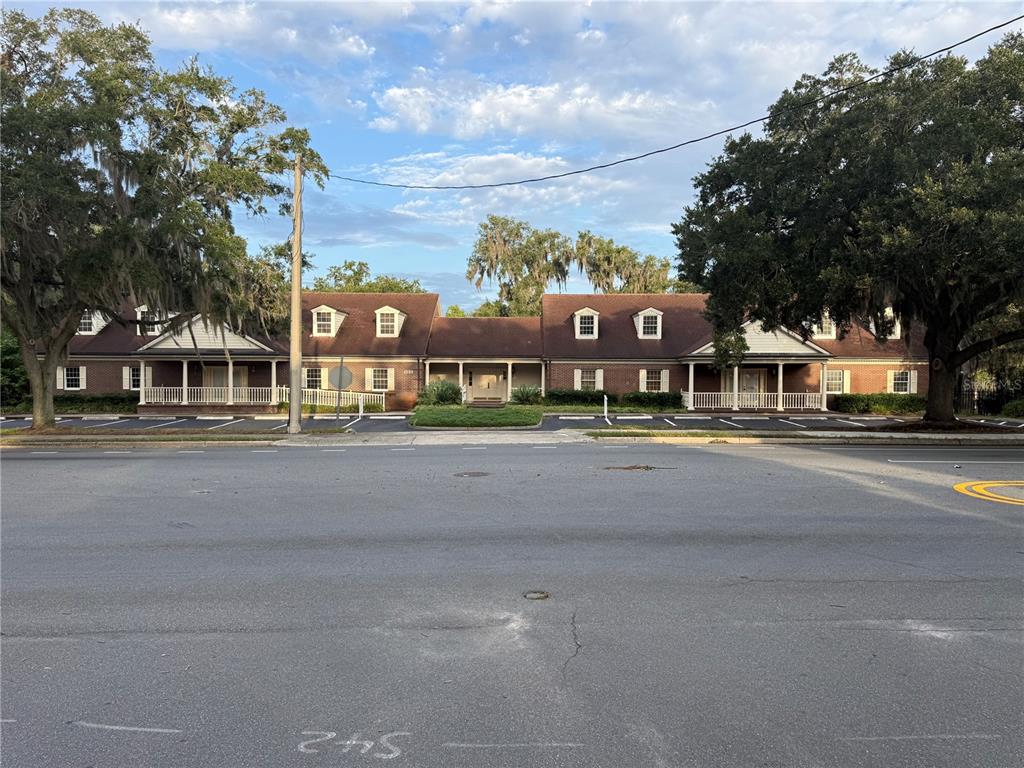 A low-rise brick commercial building with a gabled roof and covered porches sits behind parking — 500 NE 8TH AVENUE, OCALA, FL