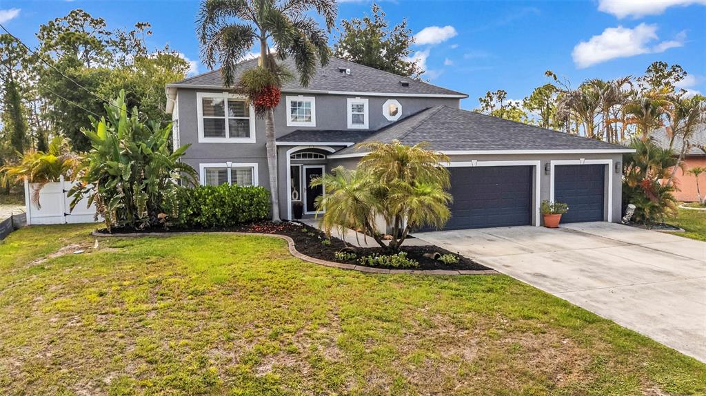 A two-story gray house features a dark shingled roof, a two-car garage, and landscaping — 2837 KALSTED STREET, NORTH PORT, FL
