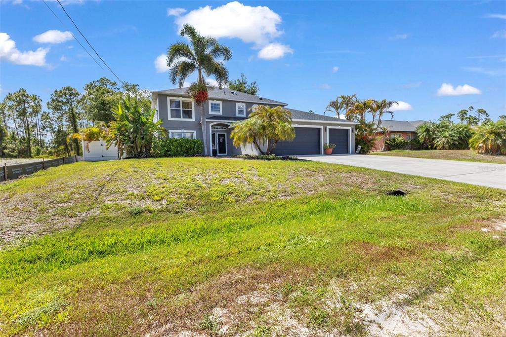 A two-story gray house with a three-car garage sits on a grassy, sloped lot — 2837 KALSTED STREET, NORTH PORT, FL