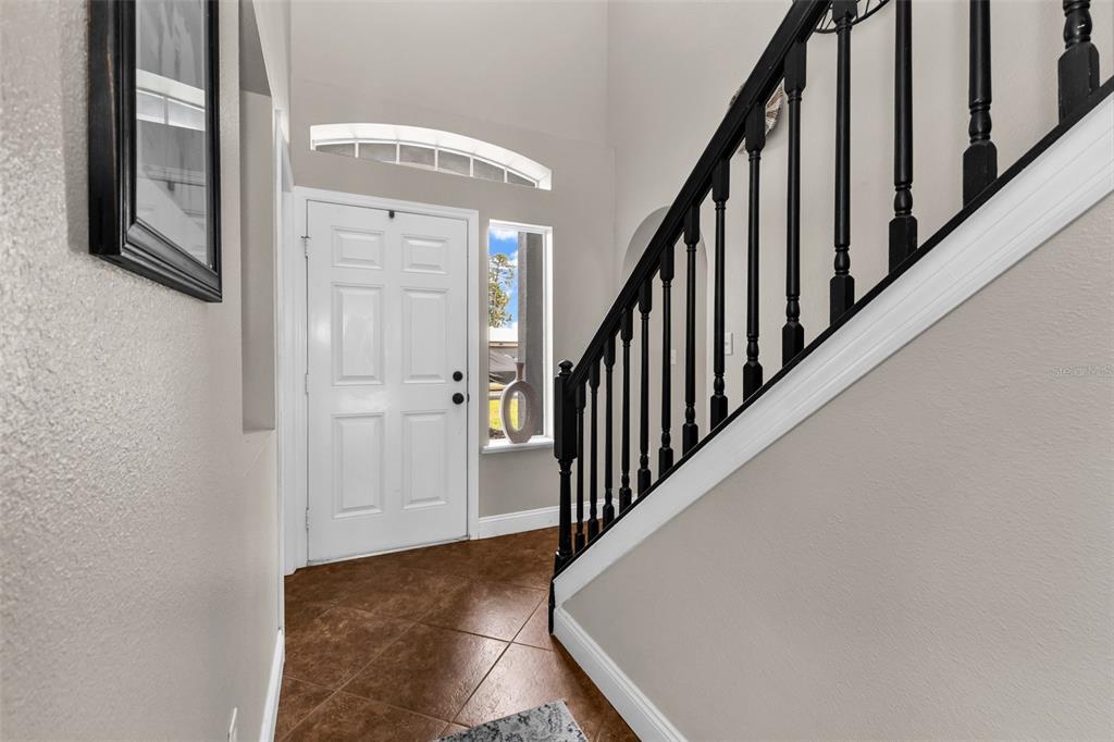 An entryway features tile flooring, a white front door, and a staircase with black railings — 2837 KALSTED STREET, NORTH PORT, FL