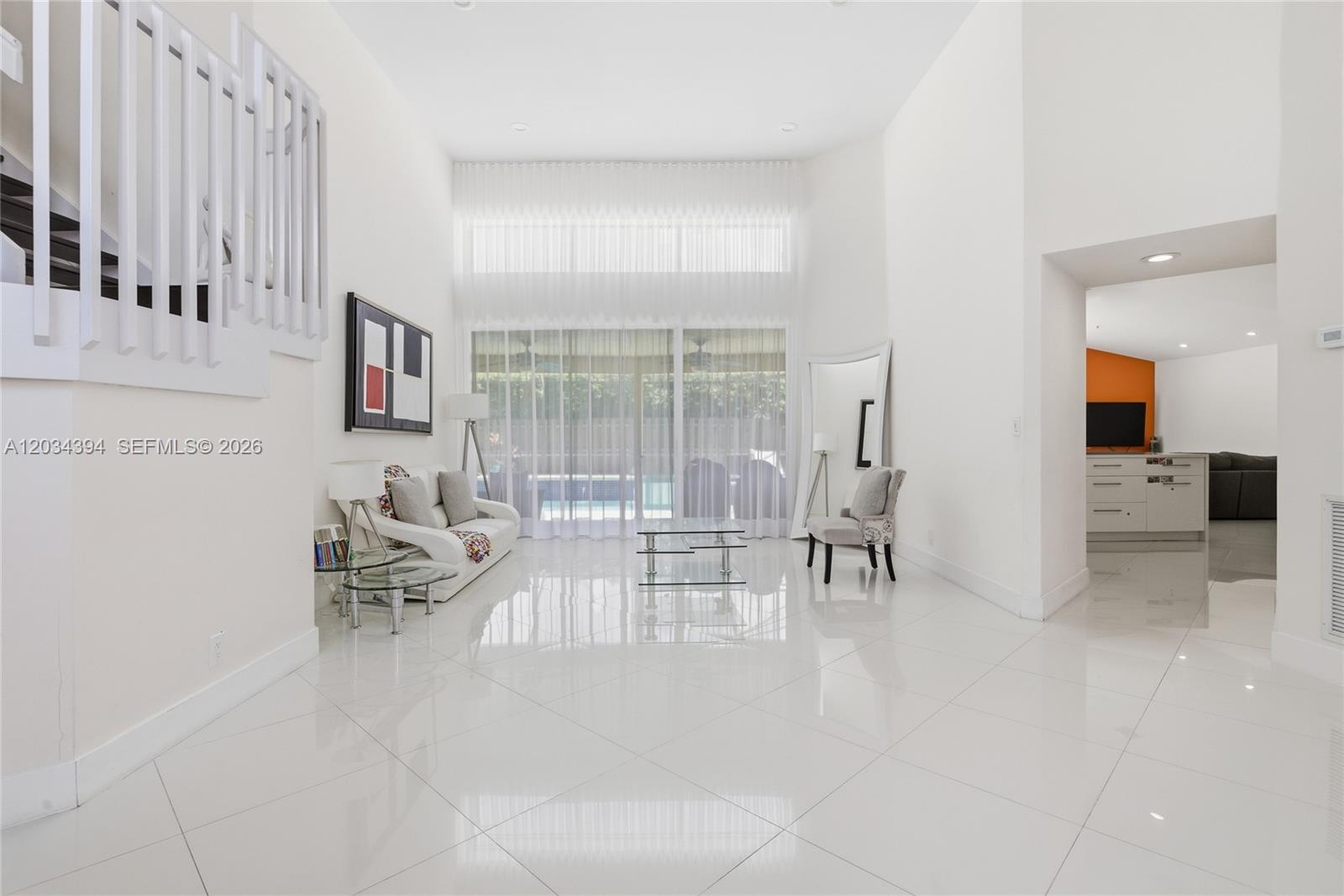 A bright, high-ceilinged living room features white tile floors, a sofa, and glass tables — 9612 N Carousel Cir N, Boca Raton FL 33434, BOCA RATON, FL