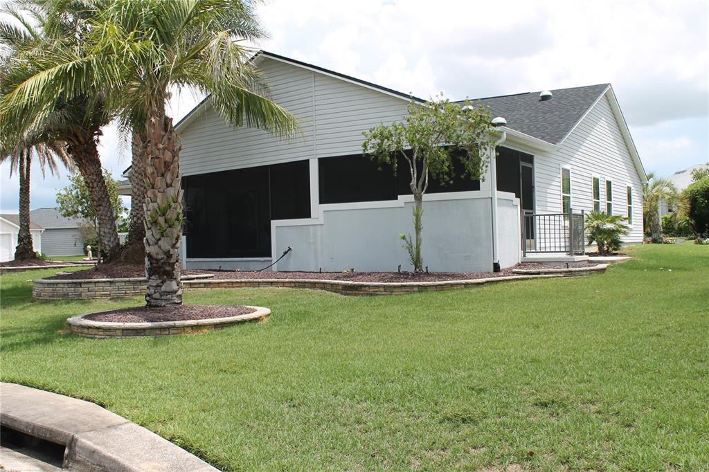 A white house with a screened-in porch and a landscaped yard with palm trees — 2440 KATE HILL STREET, THE VILLAGES, FL