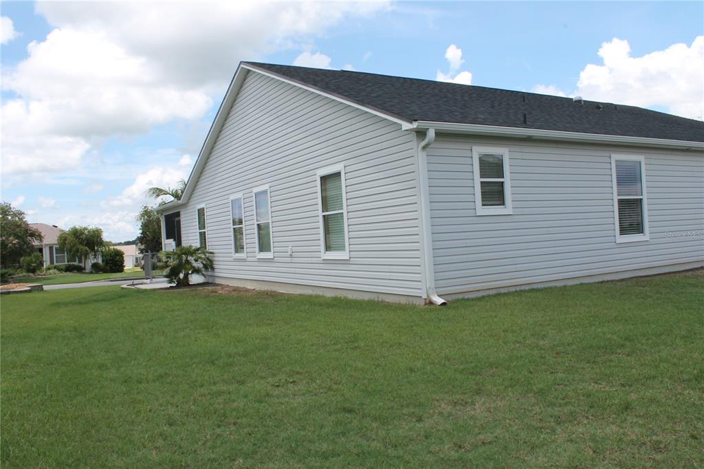 A side view of a light gray vinyl-sided house with a dark shingled roof — 2440 KATE HILL STREET, THE VILLAGES, FL