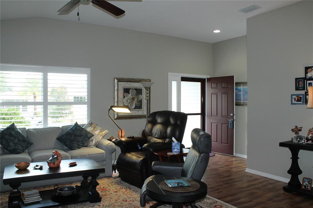 A living room features a sofa, leather recliners, a coffee table, and a dark entry door — 2440 KATE HILL STREET, THE VILLAGES, FL