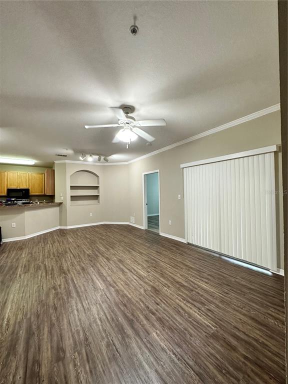An open-concept living area features wood-look flooring, a ceiling fan, and a built-in wall niche — 10023 COURTNEY PALMS BOULEVARD UNIT 101, TAMPA, FL