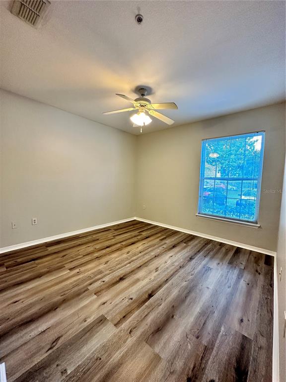 An empty bedroom features light-colored walls, a ceiling fan, and wood-look flooring — 10023 COURTNEY PALMS BOULEVARD UNIT 101, TAMPA, FL