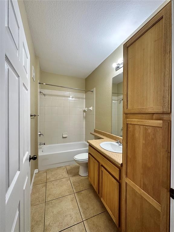 A bathroom features a tub-shower combo, a wood vanity with a sink, and tile flooring — 10023 COURTNEY PALMS BOULEVARD UNIT 101, TAMPA, FL