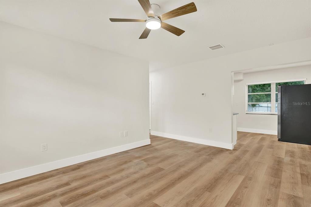 An interior view shows a room with light-colored walls, wood-look flooring, and a ceiling fan — 5543 GULF DRIVE, NEW PORT RICHEY, FL