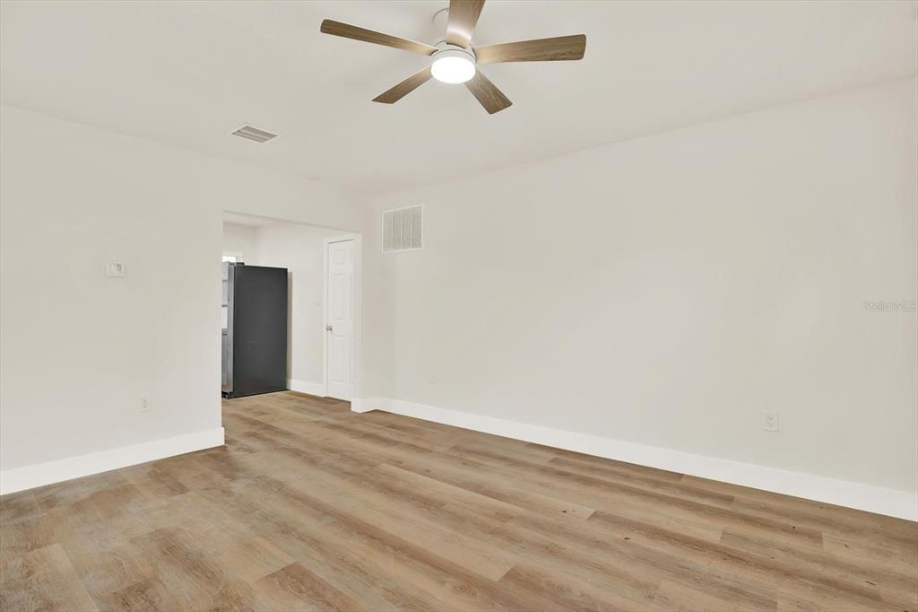 A room with light-colored walls, wood-look flooring, and a ceiling fan — 5543 GULF DRIVE, NEW PORT RICHEY, FL