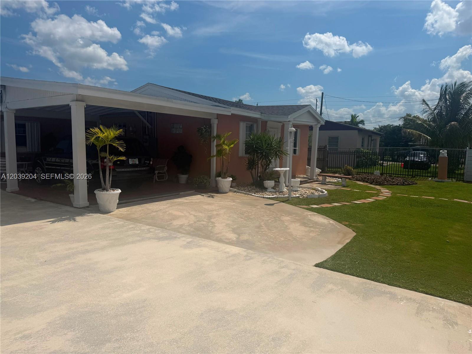 A single-story house with a carport, a paved driveway, and a landscaped front yard — 12150 SW 213th Ter, Miami FL 33177, MIAMI, FL