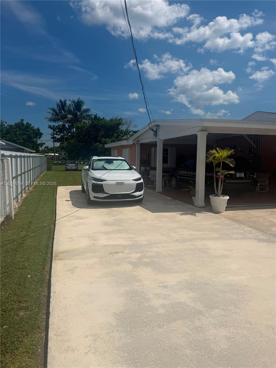 A white Audi SUV is parked in the driveway of a house with a carport — 12150 SW 213th Ter, Miami FL 33177, MIAMI, FL