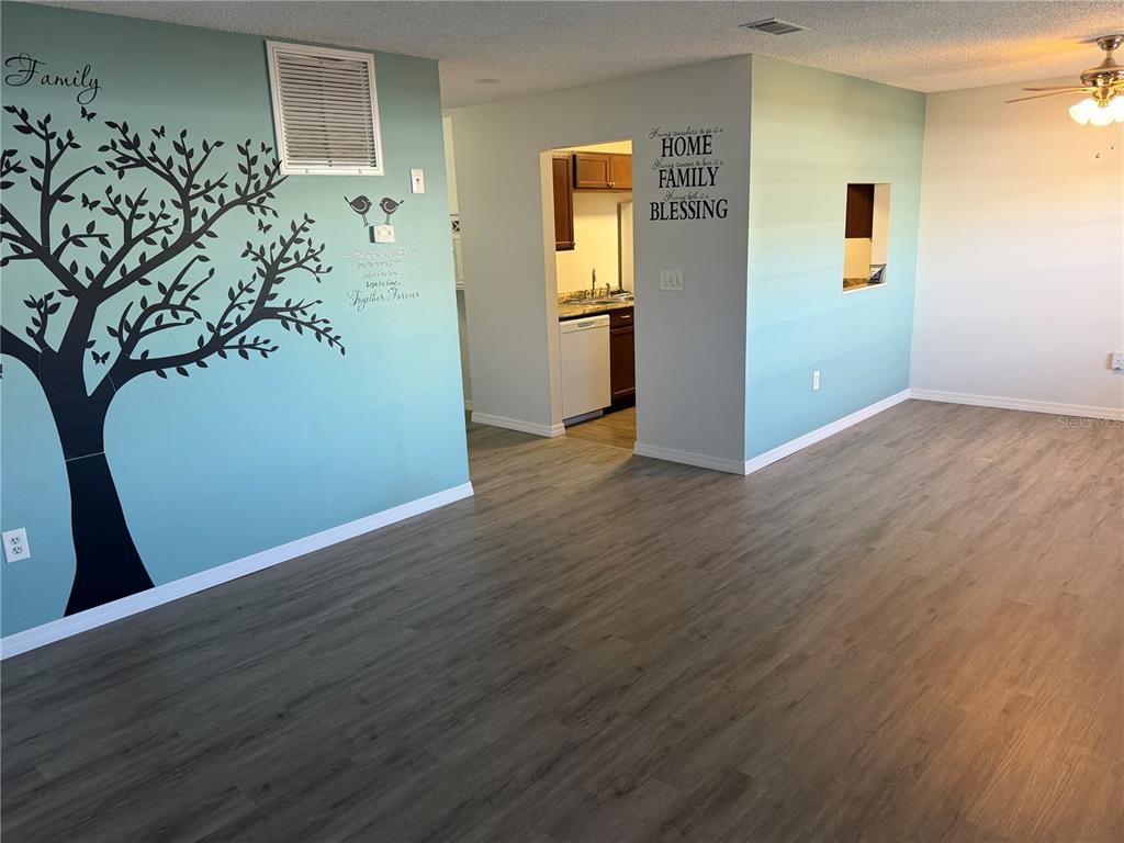 A living room with light blue walls, a tree decal, and wood-look flooring — 5967 TERRACE PARK DRIVE N UNIT 104, ST PETERSBURG, FL