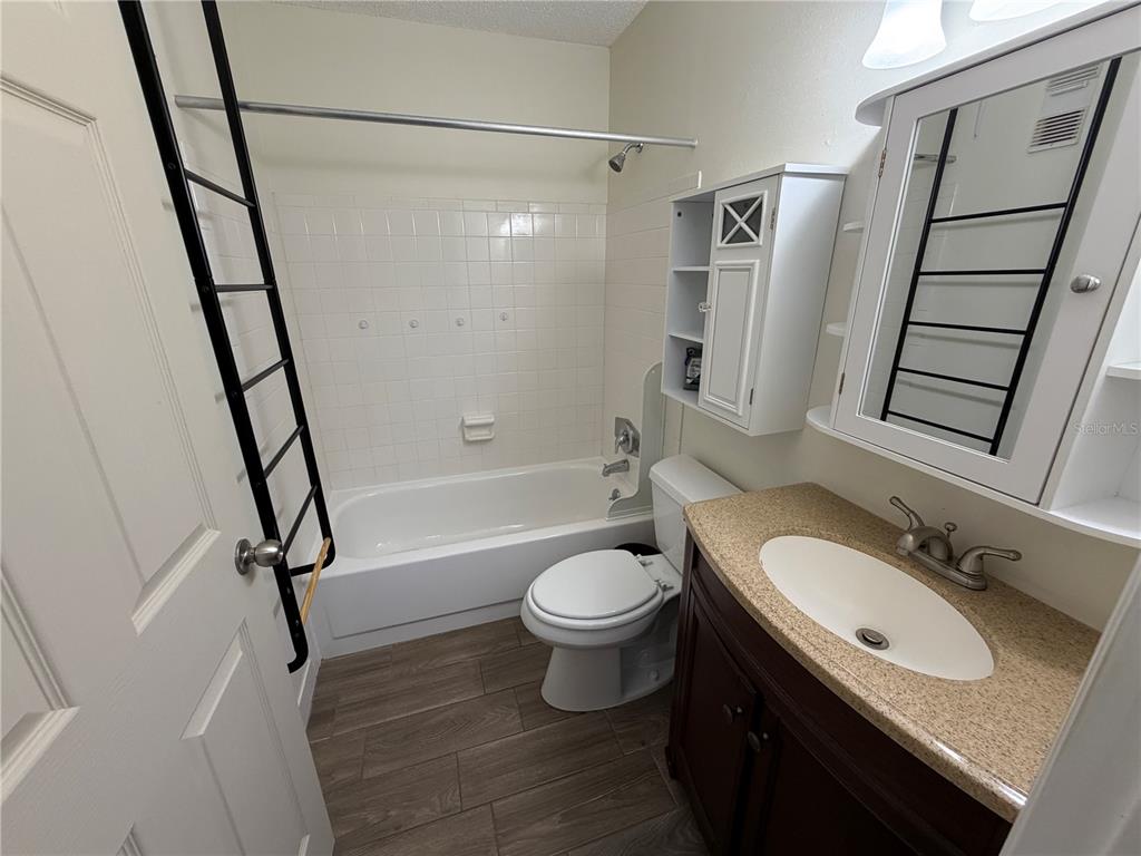 A bathroom features a tub-shower combination, a white toilet, and a dark wood vanity — 5967 TERRACE PARK DRIVE N UNIT 104, ST PETERSBURG, FL