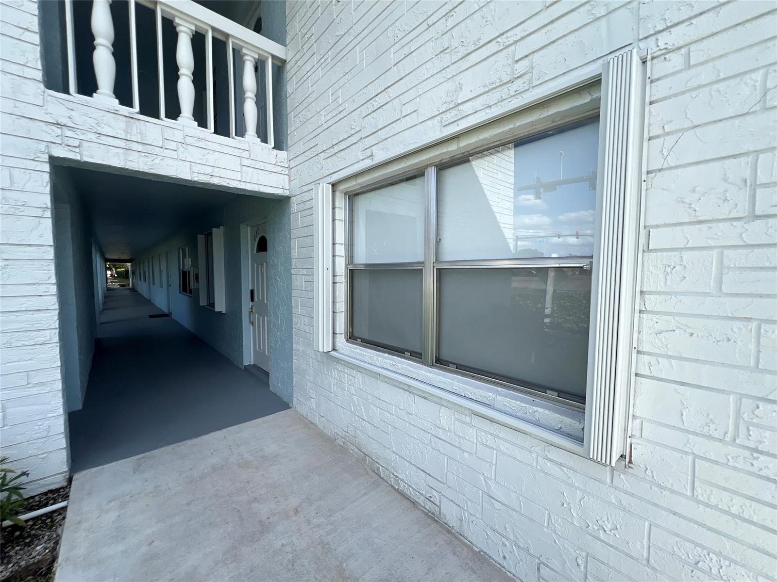 A white brick exterior wall features a large window and a covered outdoor walkway — 9780 Marina Boulevard # 415, Boca Raton FL 33428, BOCA RATON, FL