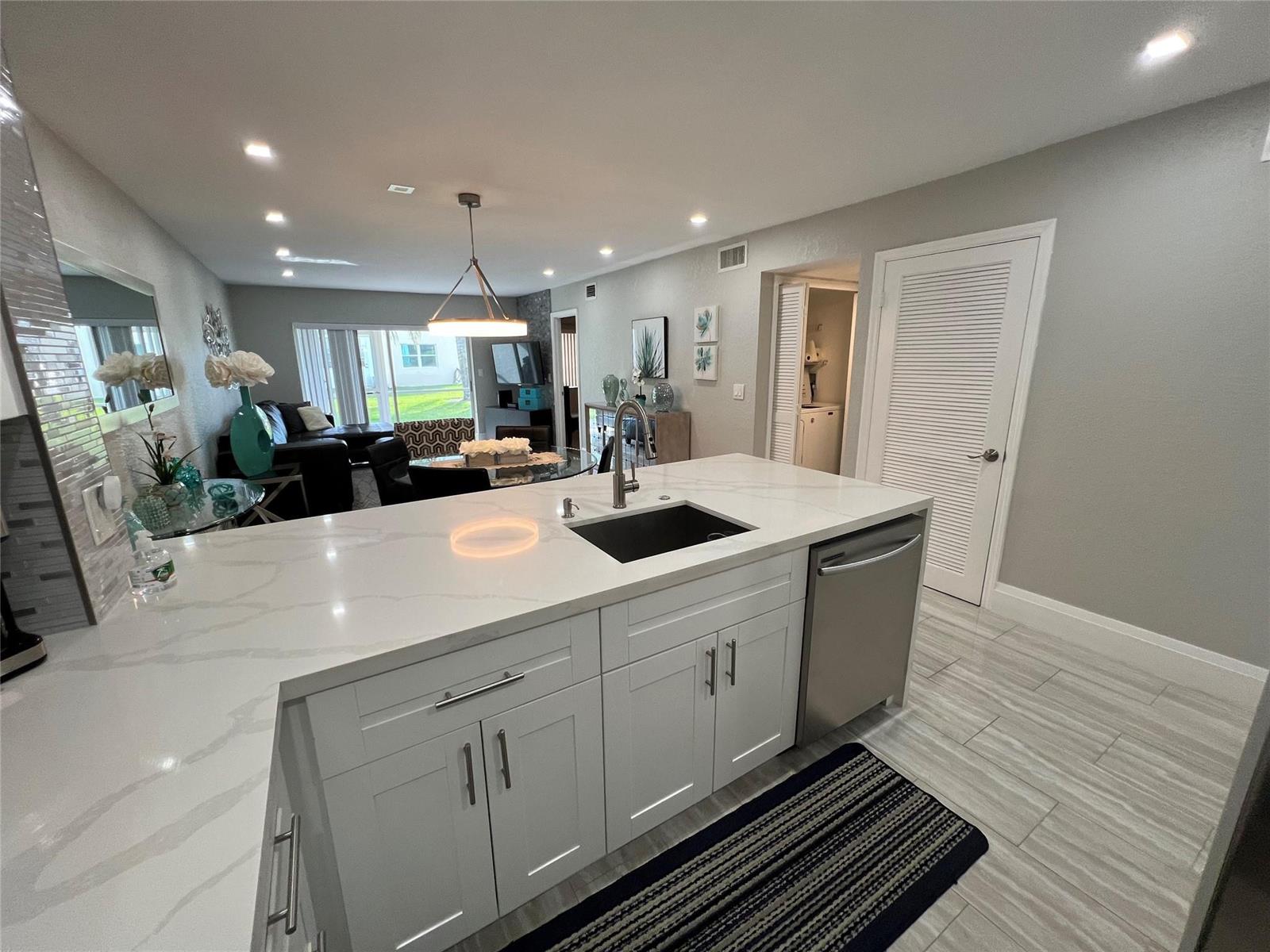 A modern kitchen features white cabinets, a quartz countertop, and an island with a sink — 9780 Marina Boulevard # 415, Boca Raton FL 33428, BOCA RATON, FL