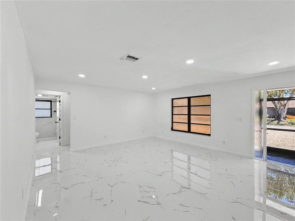 A bright room with white marble-patterned tile flooring, recessed lighting, and a glass door — 2101 HIBISCUS ROAD, FORT MYERS, FL