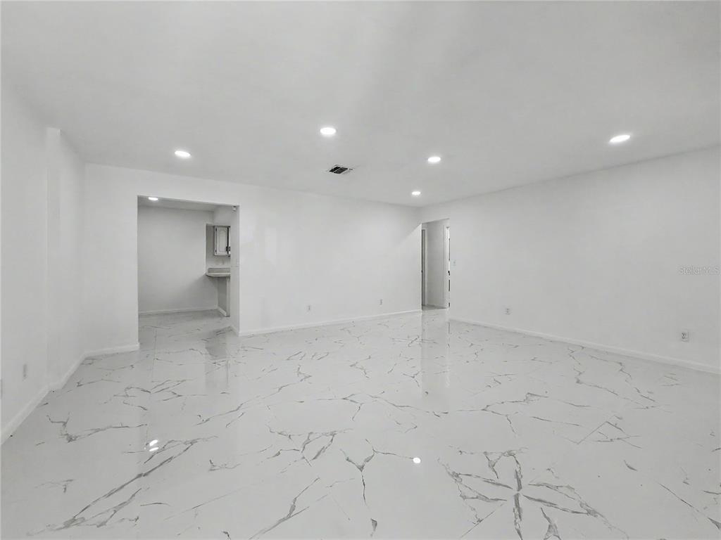A spacious, minimalist room features white walls, recessed lighting, and polished white marble-patterned tile flooring — 2101 HIBISCUS ROAD, FORT MYERS, FL