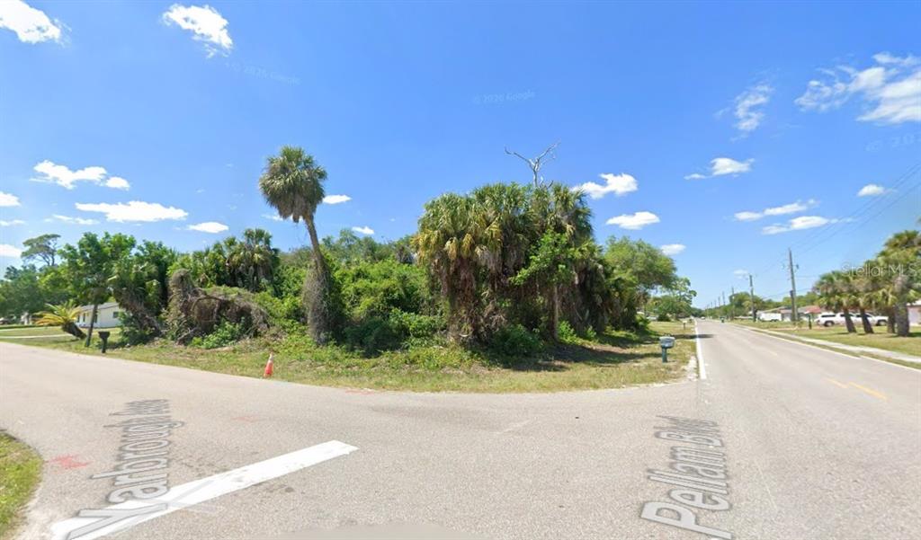 A vacant, tree-covered corner lot sits at the intersection of two paved residential streets — 18504 YARBROUGH AVENUE, PORT CHARLOTTE, FL